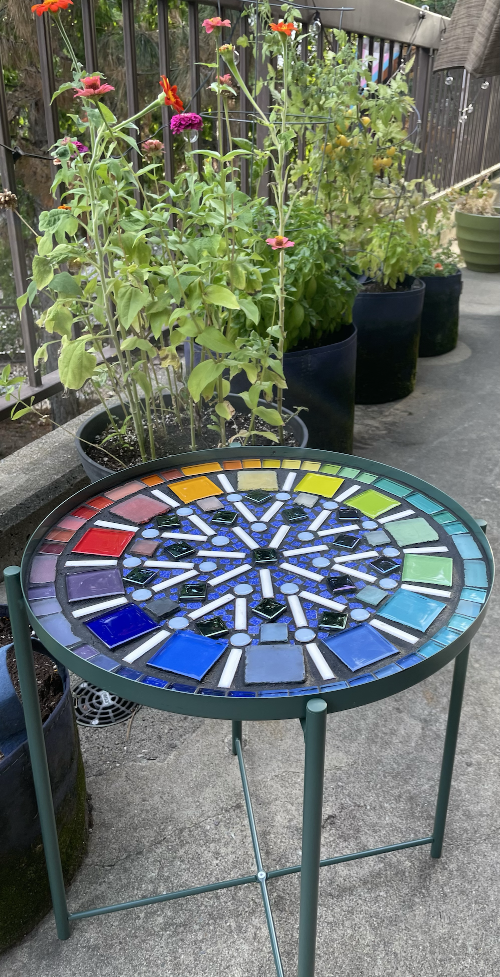 Photo of mosaic table next to plants, outside