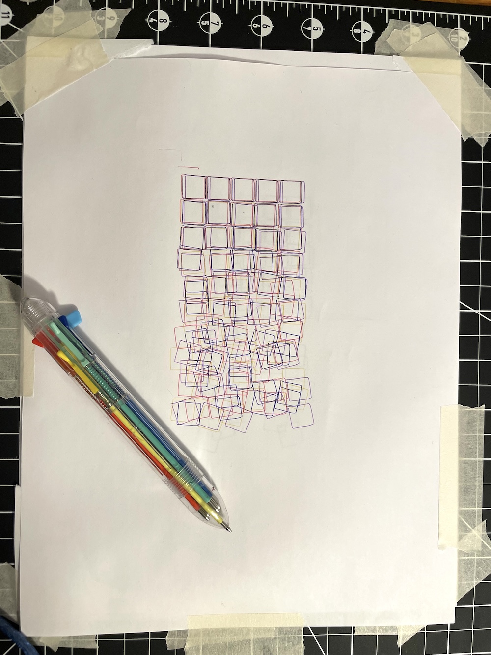 Photo of multicolor plot of drawn squares, with pen on top.